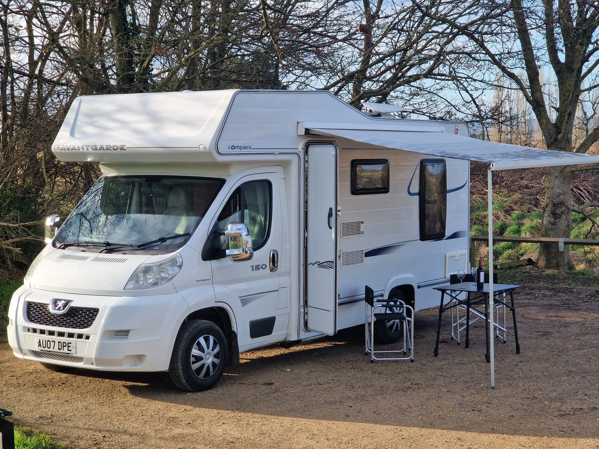 Adventure Nomad motorhome extras — BBQ, awning and camping chairs set up at a campsite